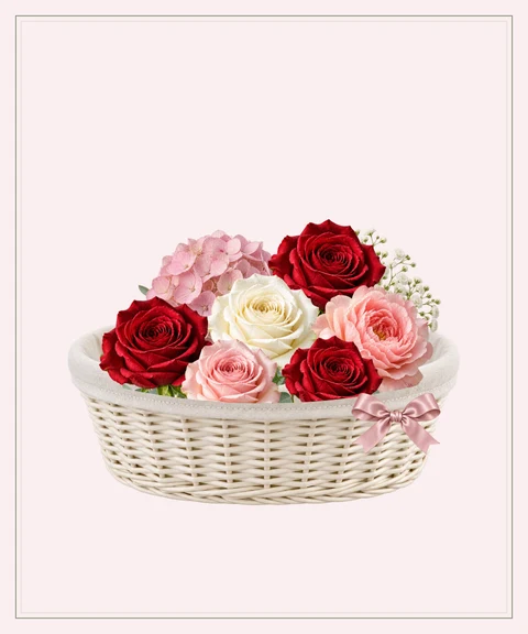 Red roses, pink hydrangeas and peonies in an ivory keepsake basket.