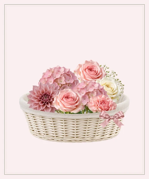 Pink hydrangeas, garden roses and a dahlia in an ivory keepsake basket.