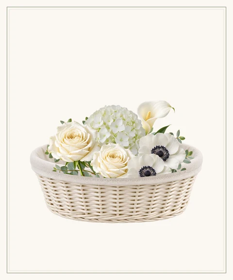 An understated ivory basket of white hydrangeas, roses and anemones.